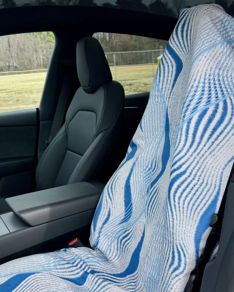 Car interior with a blue and white patterned seat cover on the driver's seat.