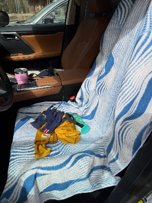 Car seat covered with a blue and white patterned cover, with clothes on it.