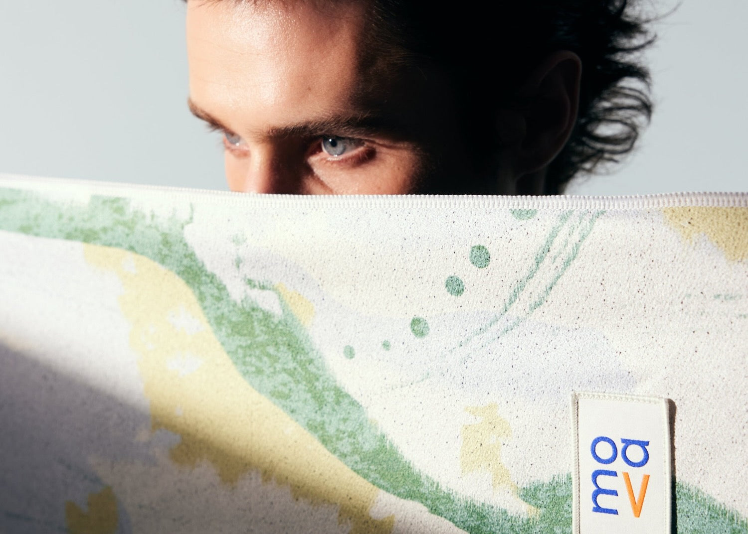 Person peeking over a car seat cover towel with a visible logo in the corner