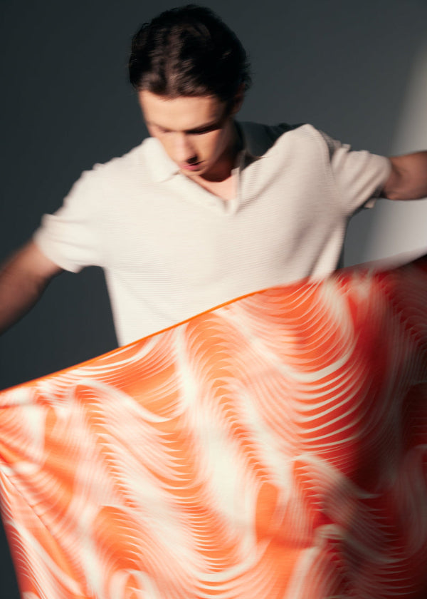 Person holding a large piece of orange towel with a swirling pattern