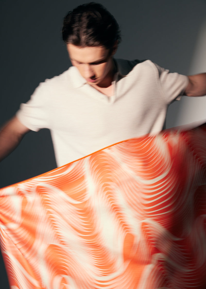Person holding a large piece of orange towel with a swirling pattern