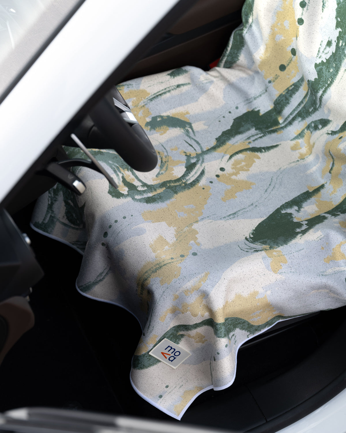 Floral-patterned towel draped over a car seat with a visible brand logo.