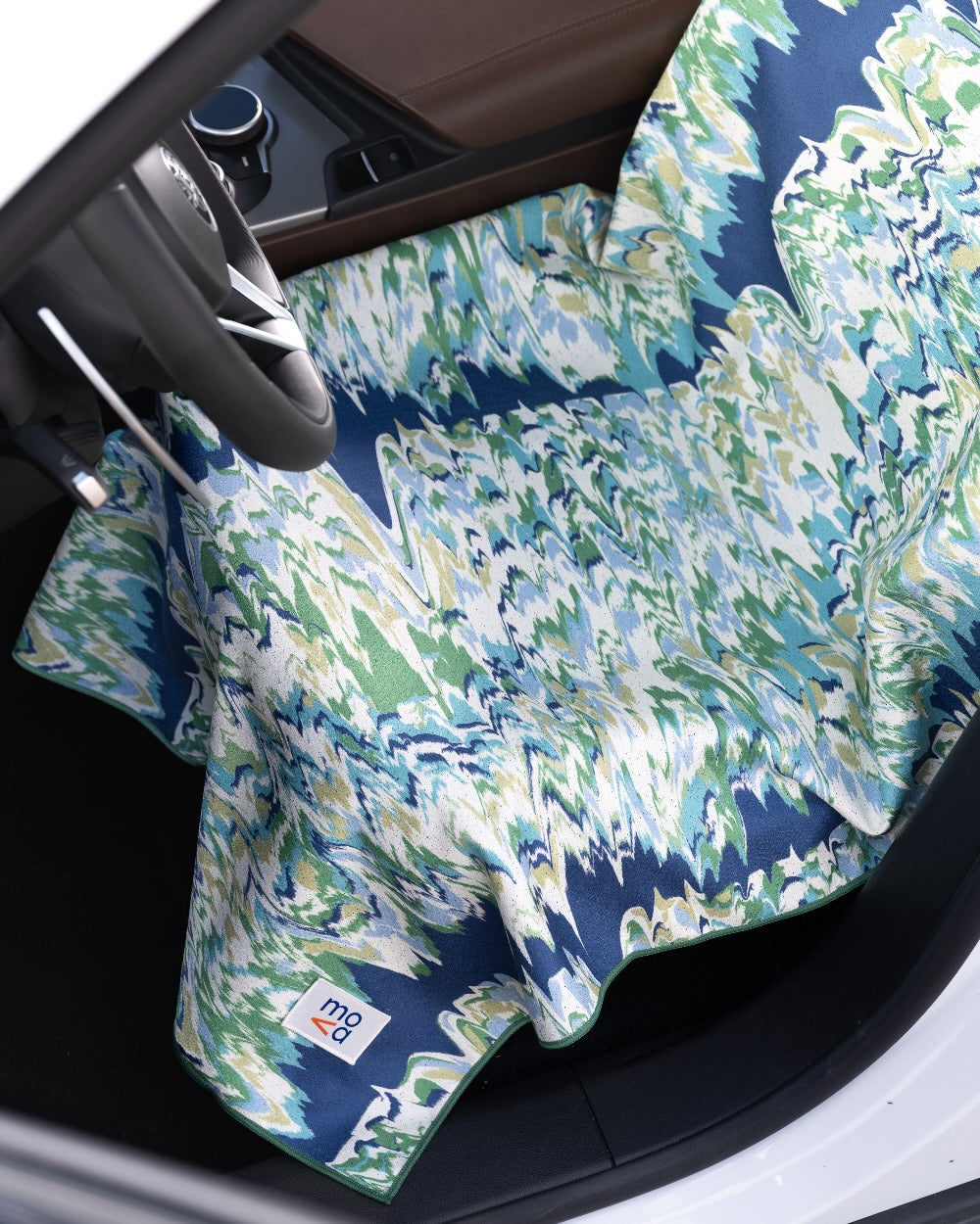 Car interior with a floral-patterned car seat cover towel over the seats and dashboard.