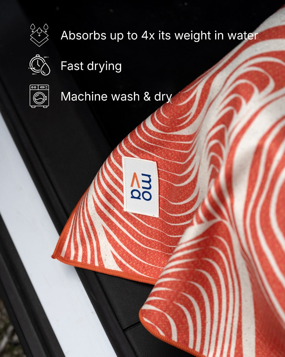 Red and white patterned car seat cover towel with a brand label, placed on a black surface.